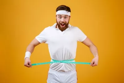 happy-bearded-fitness-man-measuring-his-waist-with-tape